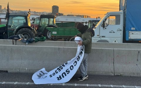 Un dels pagesos del tall a l’accés del port de Tarragona recollint la seva pancarta abans d’aixecar la mobilització.